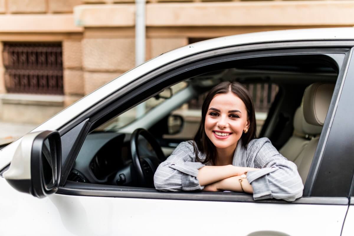 mulher feliz dentro do carro após ald - aluguer de carro de longa duração