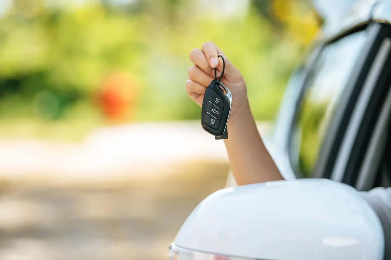 mão a segurar chave do carro através da janela de um carro branco