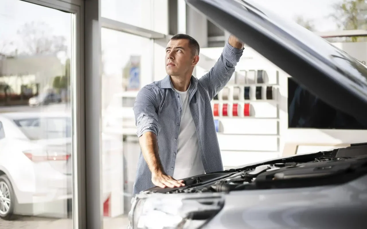 homem numa oficina a ver o motor de um carro com o capô aberto