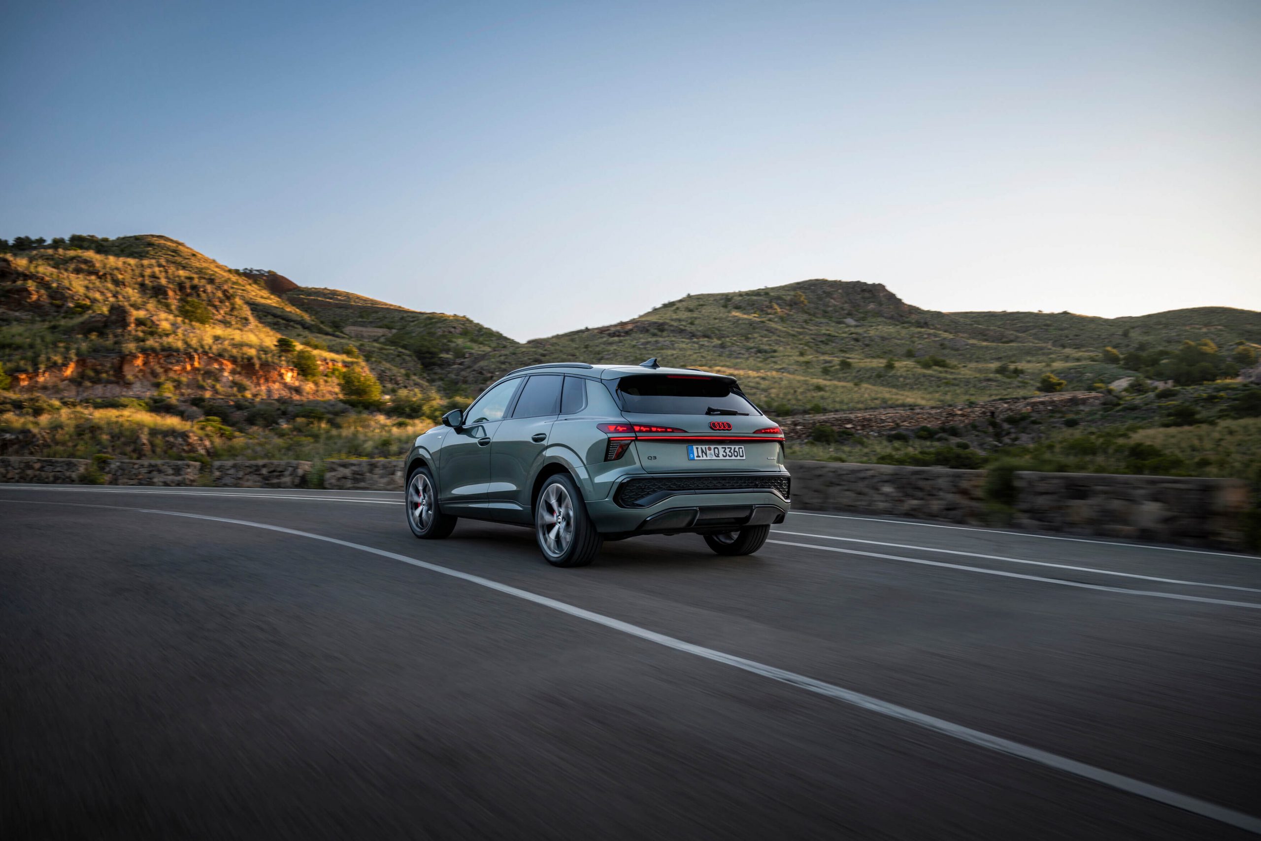 Vista exterior traseira do novo Audi Q3 2026 numa estrada no meio de montanhas